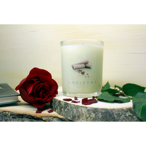 rose sandalwood candle with rose and petals with book on wooden plank